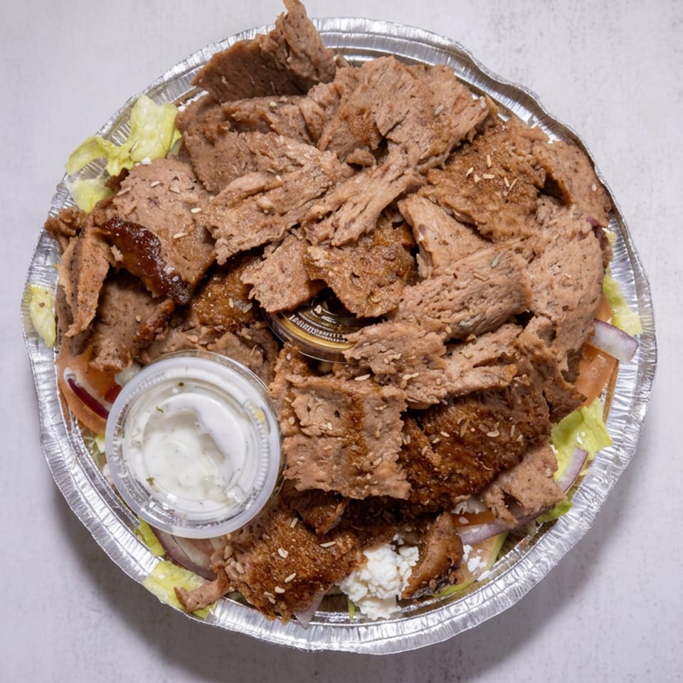 Aluminum platter piled with sliced roasted meat, lettuce, onions, white sauce, and crumbled cheese.
