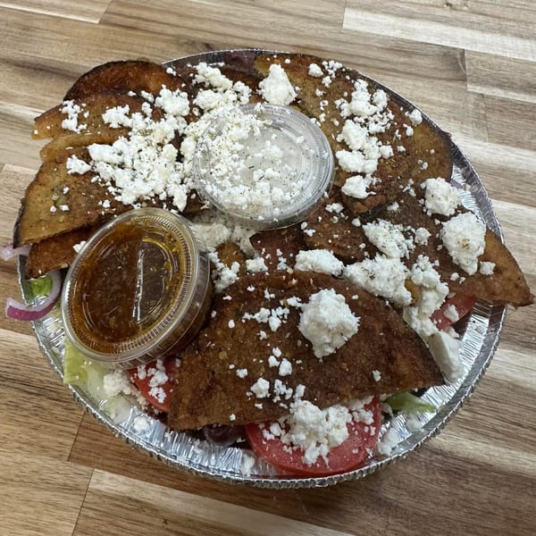 Mister Mike's Gyros' Greek nachos with feta, tomatoes, onions, and two sauces in a foil pan.